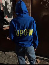 Load image into Gallery viewer, A blue sweatshirt with green UPOW writing at the back. 
